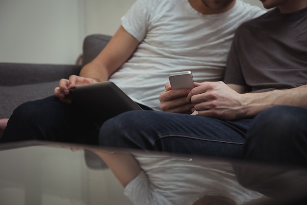 Coppia gay seduto sul divano e guardando la tavoletta digitale