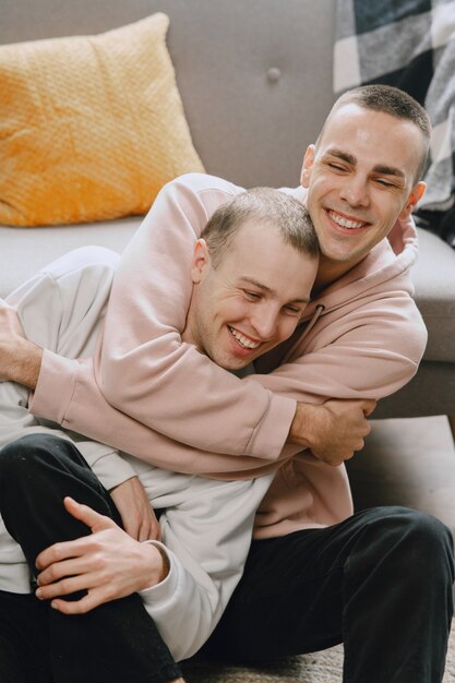 Gay couple in their apartment, hugging and siting on the floor