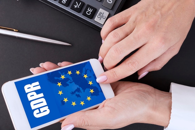 Gdpr, general data protection regulation, european data privacy law. female hand and mobile phone with eu flag and gdpr text. high quality photo