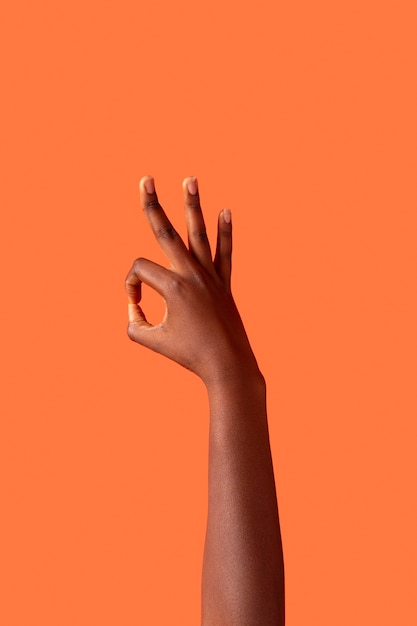 オレンジ色に分離された性別流動的な人の手