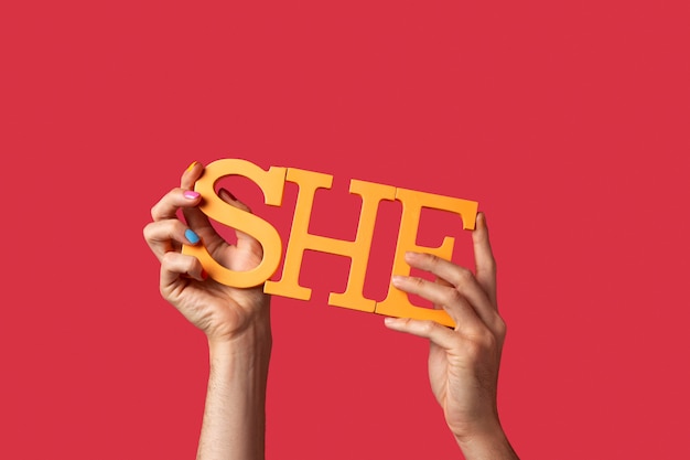 Free photo gender fluid person holding a pronoun isolated on red