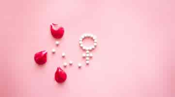 Free photo gender venus symbol made of pills and peony flower petals on a pink background