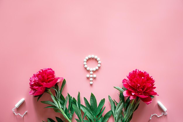 ピンクの背景に丸薬と牡丹の花で作られた性別の金星のシンボル