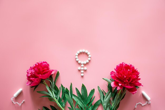 Gender venus symbol made of pills and peony flower on a pink background