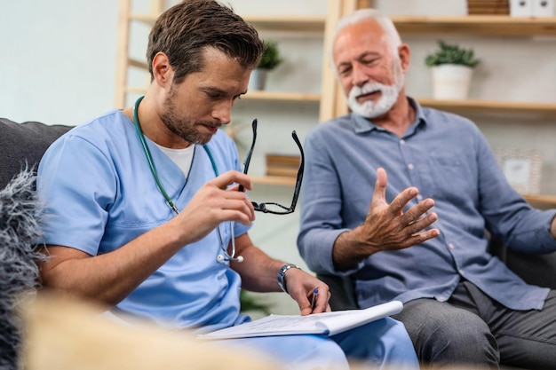 General practitioner analyzing medical documents of senior patient while being in home visit