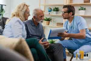 Free photo general practitioner showing to senior couple medical documents while being in home visit