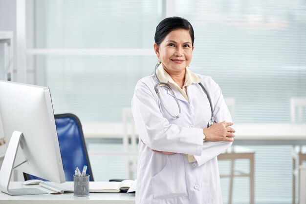 General practitioner standing arms folded in the medical office