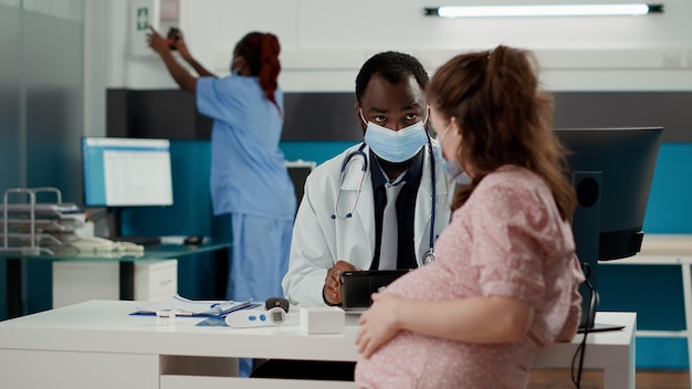 General practitioner using digital tablet at appointment with pregnant woman