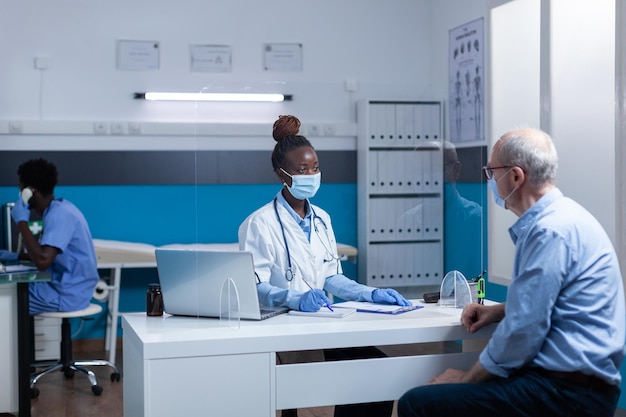 General practitionist expert talking with senior patient about ailment symptoms, treatment medicine and recovery schedule. Medic discussing with elderly man about disease report