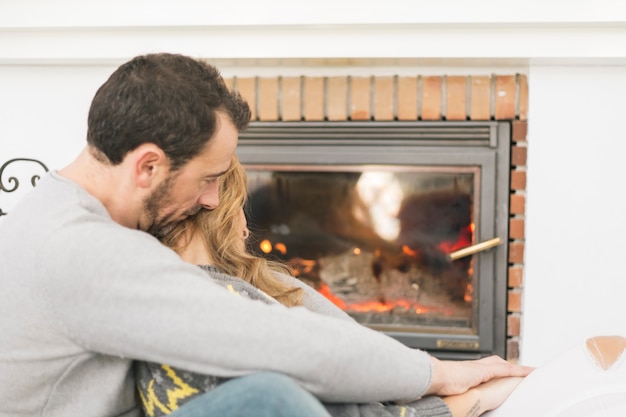 Gentle couple embracing near fireplace