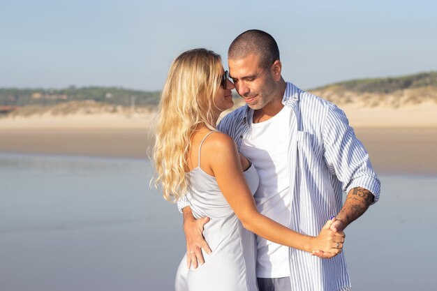 해변에서 사랑에 부드러운 커플입니다. 여름날 껴안고 춤을 추는 캐주얼 옷을 입은 남편과 아내. 휴가, 행복, 관계 개념