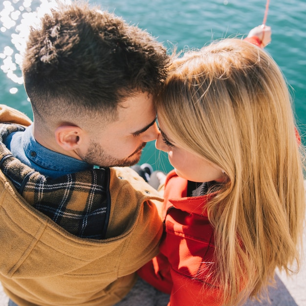 Free photo gentle couple sitting together on embankment