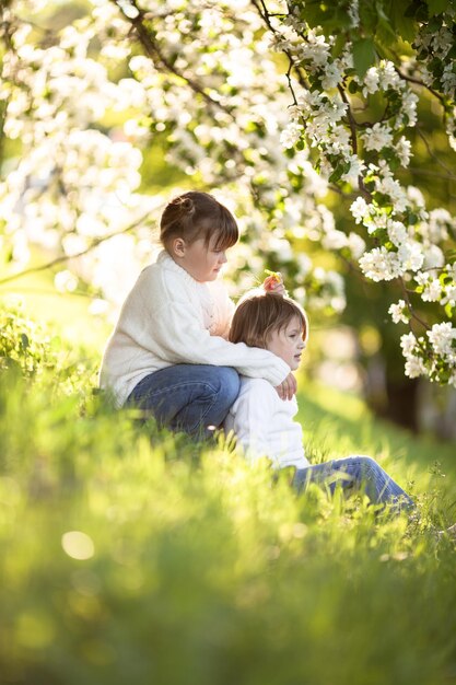 優しい姉妹がリンゴの花を抱きしめる晴れた子供時代