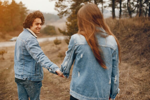 gentle and stylish couple are having a walk in the autumn park