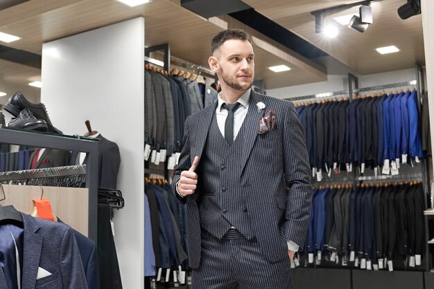 Gentleman posing in suit in showroom of boutique.
