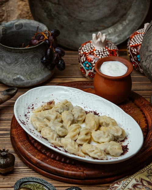 Khinkali georgiano all'interno del piatto bianco con yogurt.