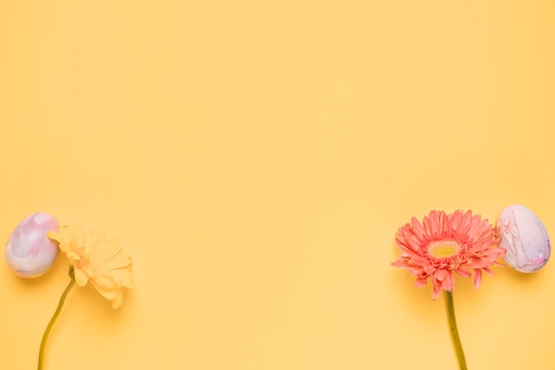 ガーベラの花とテキストを書くためのコピースペースを持つ黄色の背景の角に卵