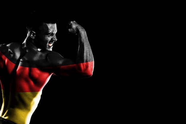 잘생긴 젊은 근육 질의 남자 검은 배경에 독일 국기