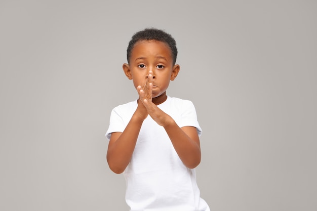 Free photo gestures, signs, symbols and body language. portrait of charming adorable african american little boy dressed casually posing isolated crossing hands in front of him, dancing, showing new moves