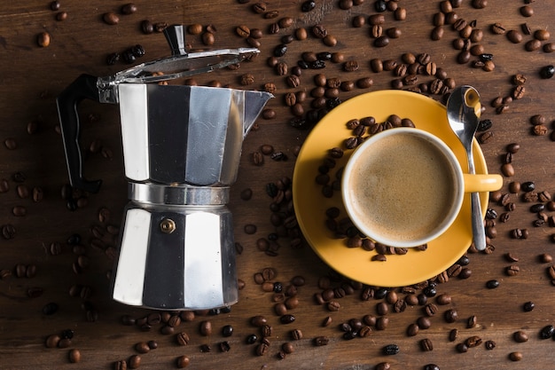 Foto gratuita macchina da caffè geyser vicino tazza gialla con cucchiaio e piatto