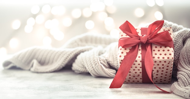 Free photo ggift in a beautiful box with a red bow and grey blanket