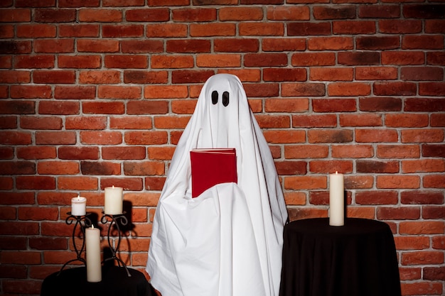 Ghost holding book over brick wall. Halloween party.