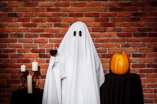 Free photo ghost holding wine over brick wall