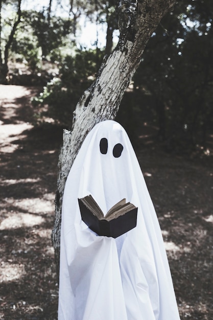 Free photo ghost standing at tree and reading book