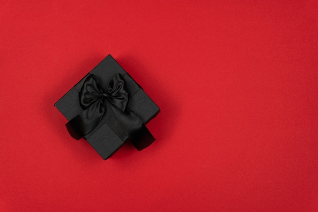 赤い背景の上のギフトブラックボックス上面図ブラックフライデークリスマスと新年のコピースペース