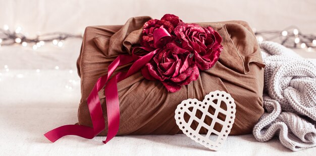 Подарочная коробка украшена лентами и декоративными розочками на вязанных изделиях. Оригинальная подарочная упаковка на день всех влюбленных.