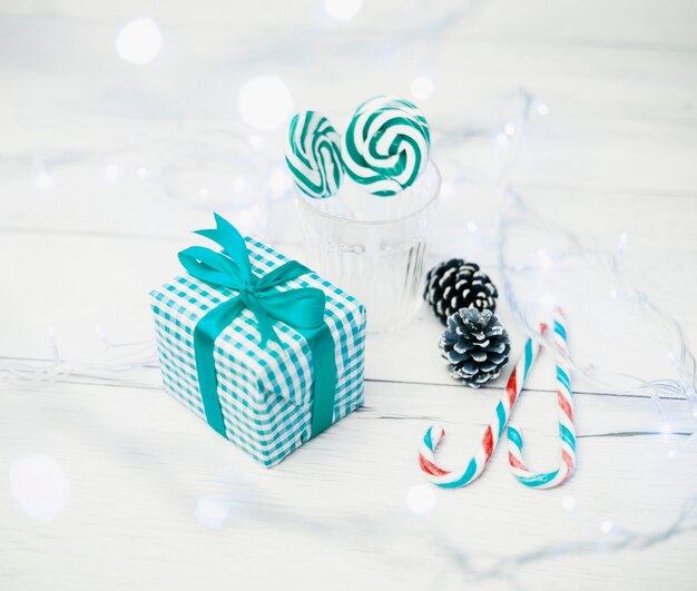 Gift box near glass with lollipops, candy canes and fairy lights