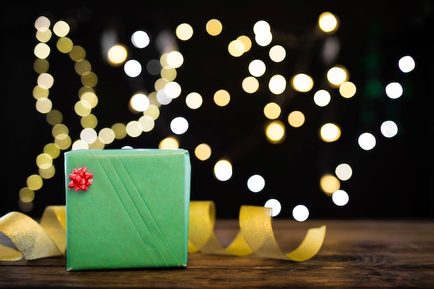 Gift box and ribbon near garland lights