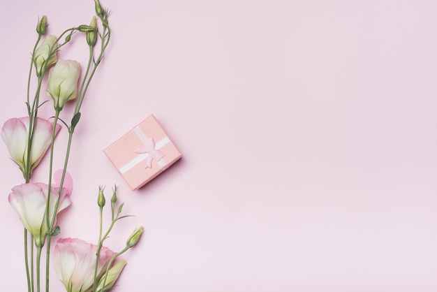 Gift box with eustoma flowers on pink background