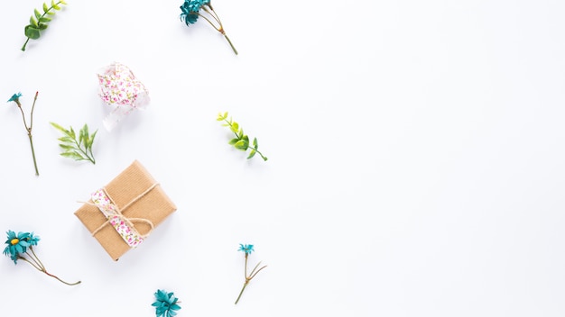 Gift box with flower branches on white table