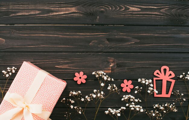 Gift box with flower branches on wooden table