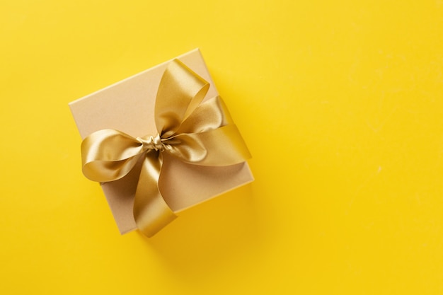 Gift box with golden ribbon on bright background