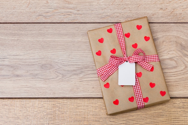 Gift box with hearts on wooden table 