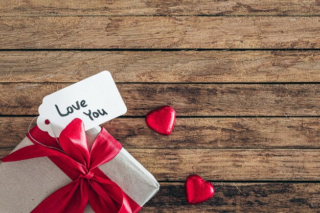 Free photo gift box with love you gift tag and heart shaped candies on wooden background