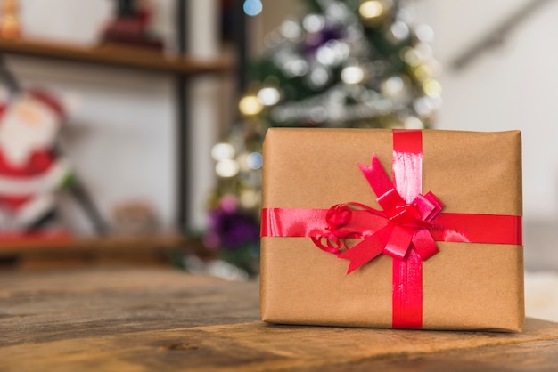 Gift box with red ribbon on table