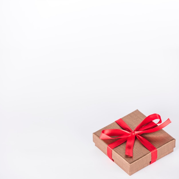 Gift box with red ribbon on table