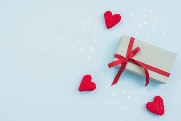 Gift box with red toy hearts on table