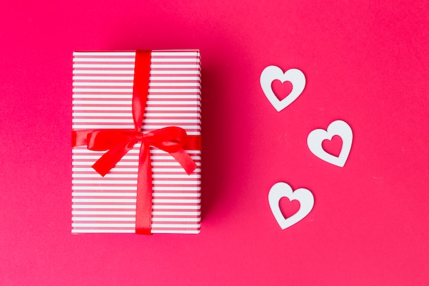 Gift box with white hearts on table 