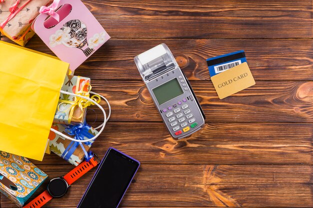 Gift boxed; wristwatch; mobile phone; payment terminal and bank card on wooden table