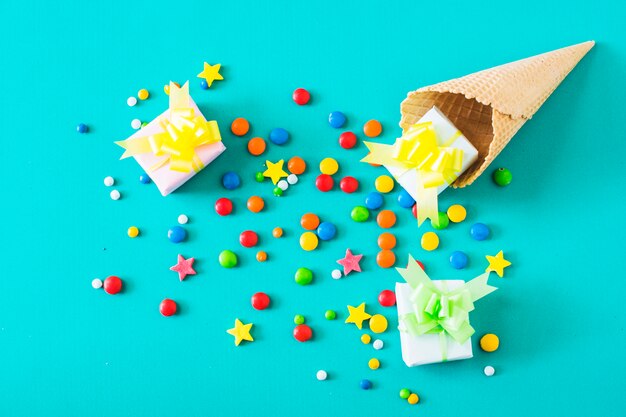 Gift boxes; candies and waffle ice cream cone on turquoise background