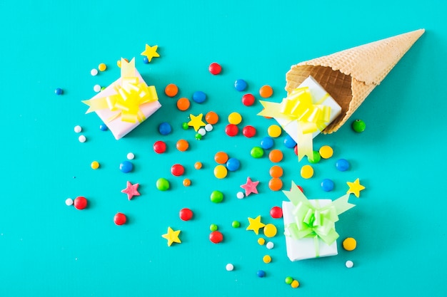 Gift boxes; candies and waffle ice cream cone on turquoise background