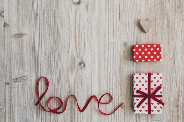 Gift boxes, a heart and the word "love" on a wooden table