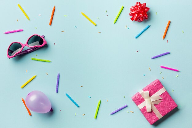 Gift boxes; sunglasses; ribbon bow; balloon; colorful candles and sprinkles on blue background