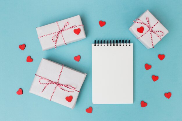 Gift boxes with notepad and red hearts on table