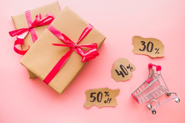 Gift boxes with red bows near shopping trolley