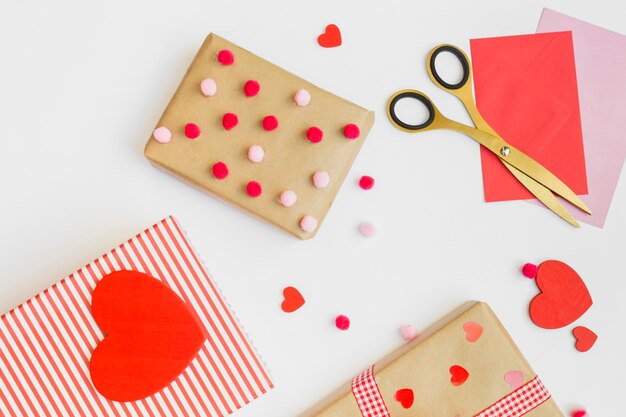 Gift boxes with small red hearts on white table